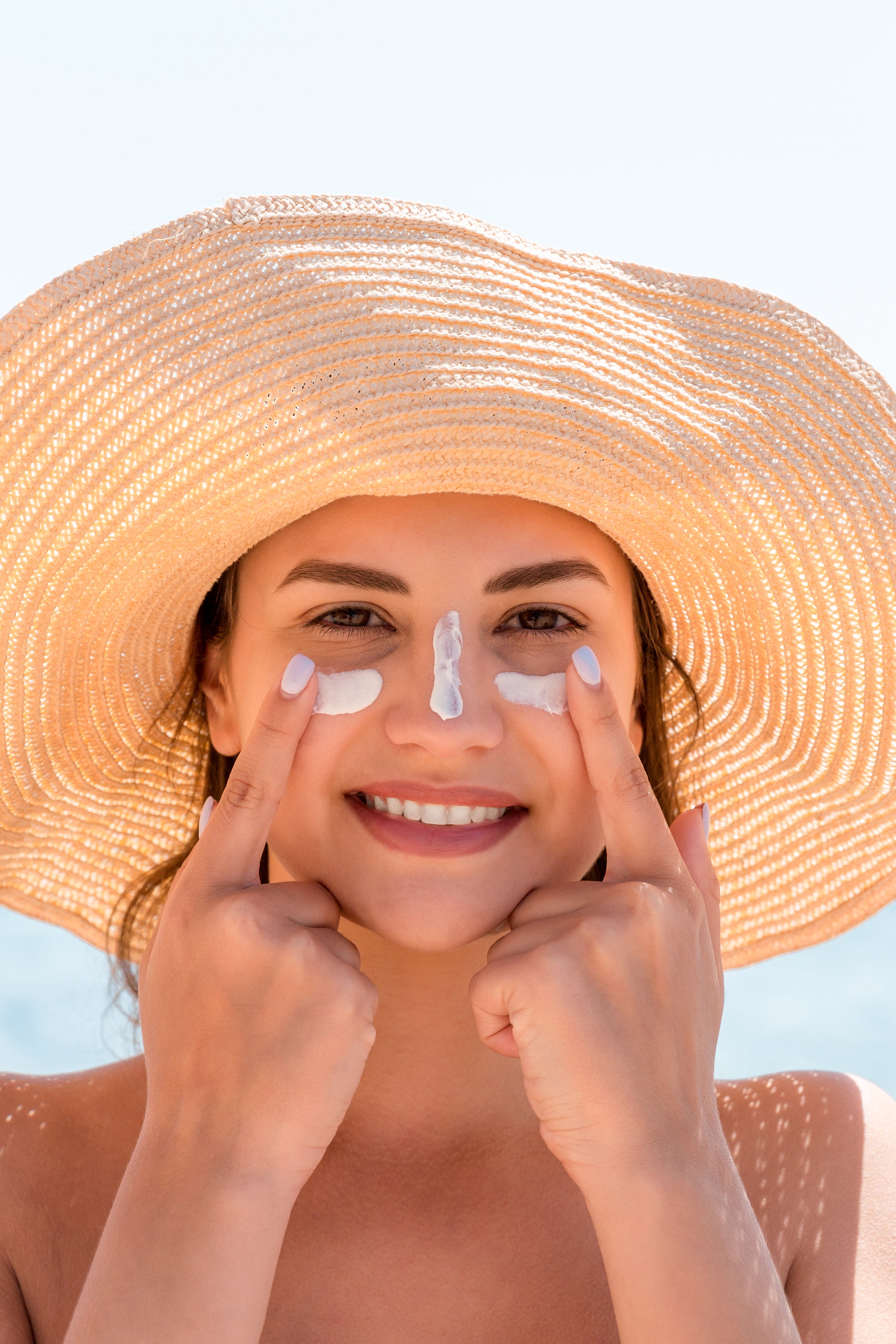Mujer sonriente con sombrero usando protector solar Sun of Ibiza – Cosmética solar Locco Ibiza
